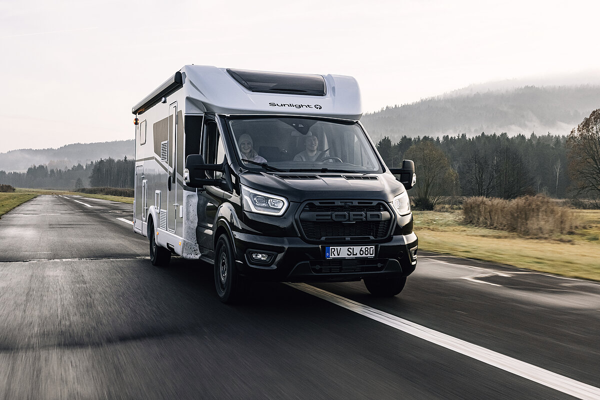Teilintegriertes Wohnmobil mit schwarzer Front auf einer Straße.