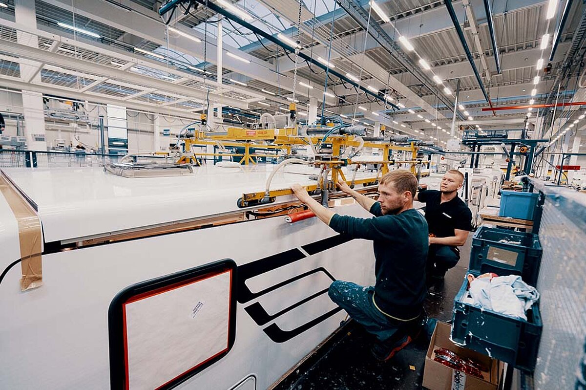 Wir sind Ihre Wohnwagen-Werkstatt in Naumburg bei Leipzig. Zwei Techniker von Caravan Rossol arbeiten am Dach eines Wohnwagens.