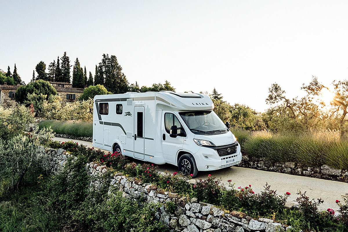 Wir verkaufen mehr als nur Wohnmobile. Ein Wohnmobil fährt über einen malerischen Feldweg.