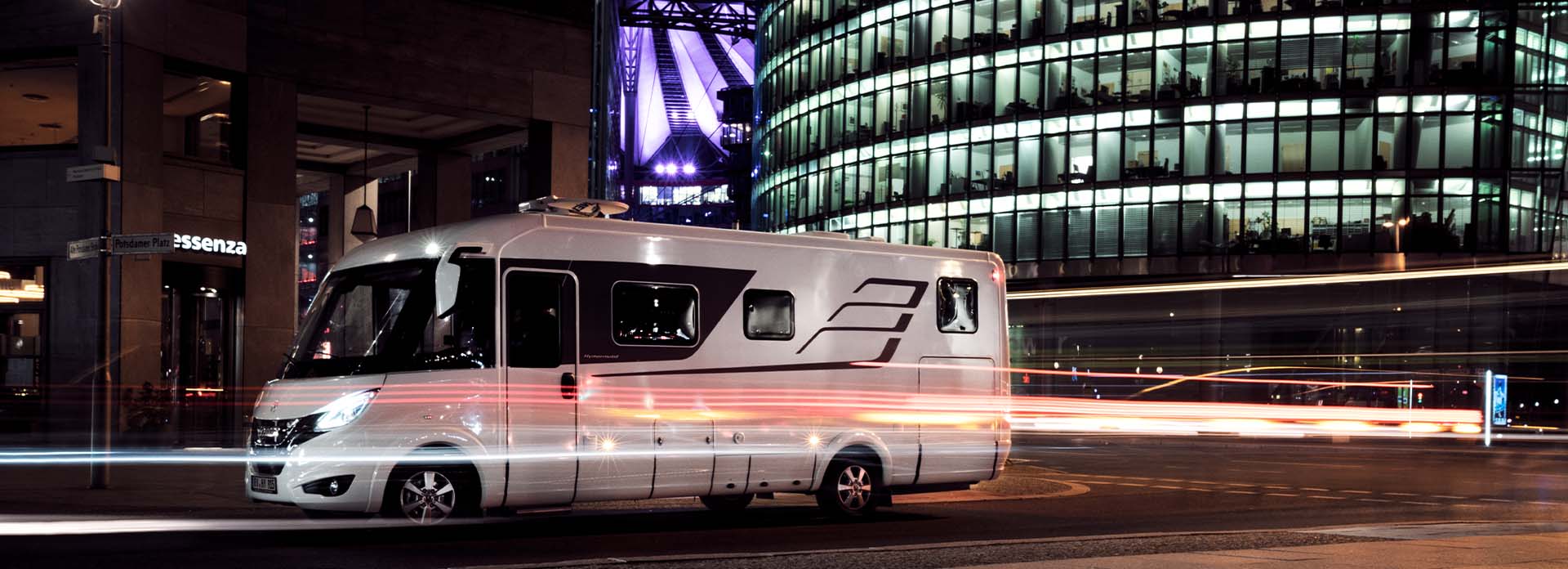 Ein Wohnmobil steht inmitten einer beleuchteten Stadt.