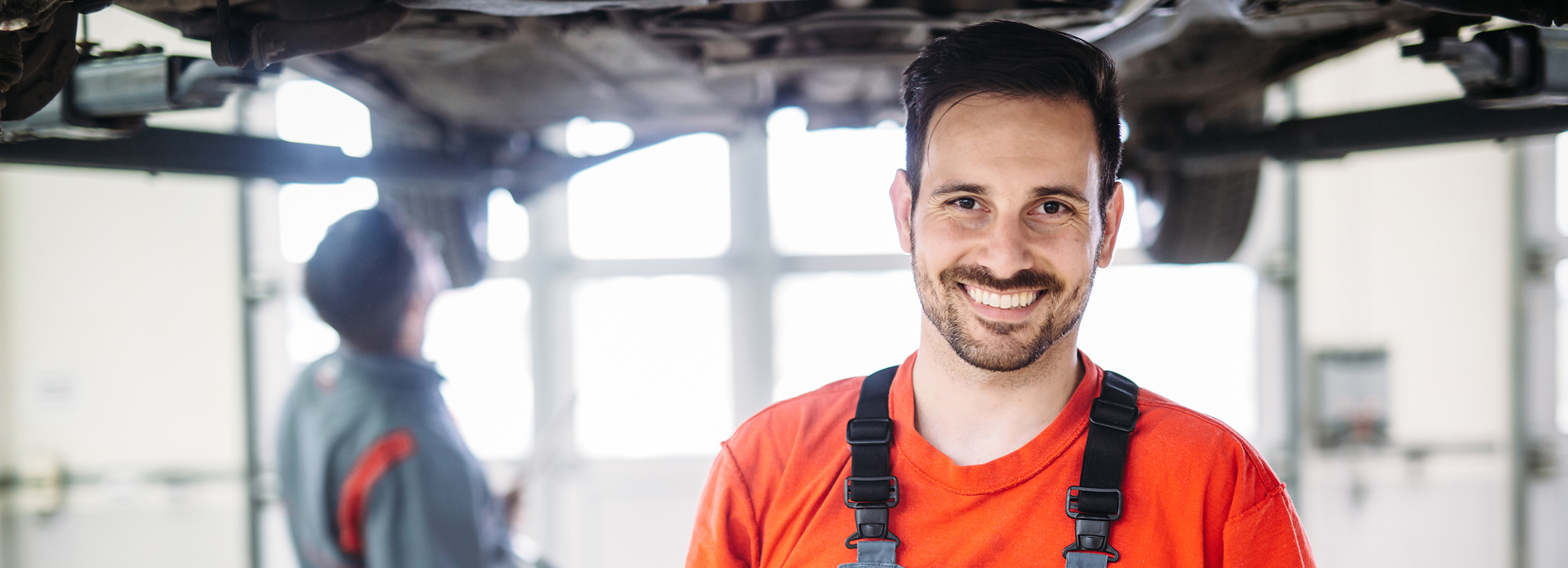 Ein Werkstattmitarbeiter von Caravan Rossol steht lächelnd unter dem Boden eines Fahrzeugs.