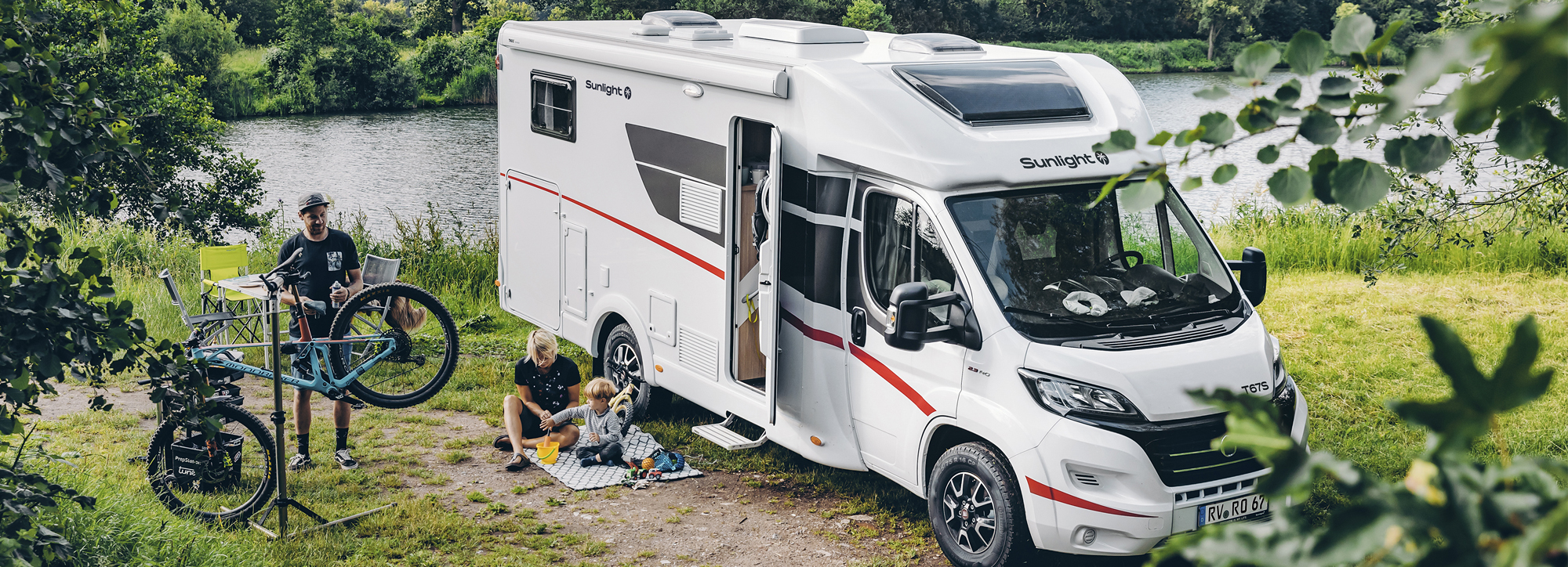 Eine Familie steht mit Fahrrädern neben einem Wohnmobil von Sunlight.
